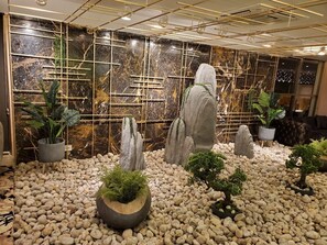 Un jardin intérieur moderne agrémenté de rochers, de plantes en pot et d’un mur décoratif.