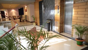 Un vestíbulo de hotel con una escalera, una zona de estar y plantas en macetas.