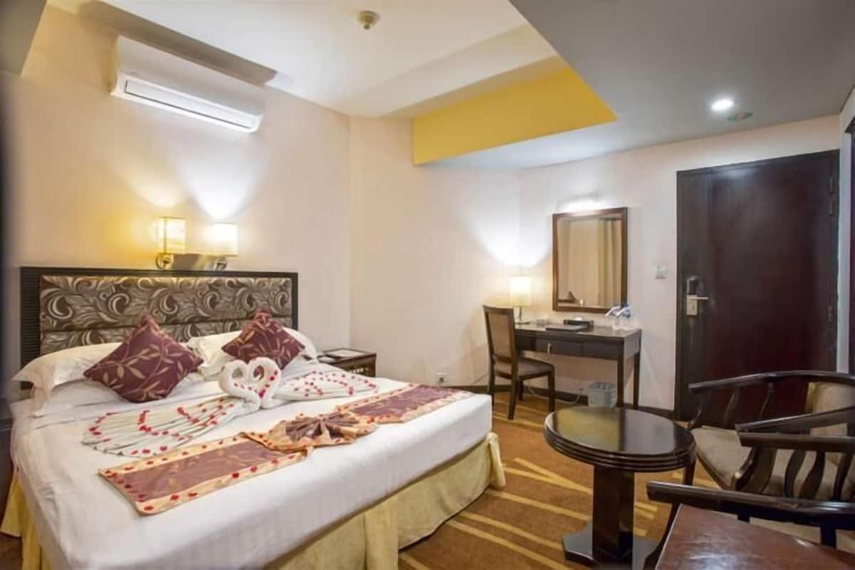 Habitación de hotel con cama, escritorio, silla y una mesa redonda.