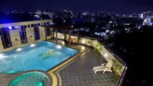 Una piscina en la azotea con vistas a la ciudad de noche.