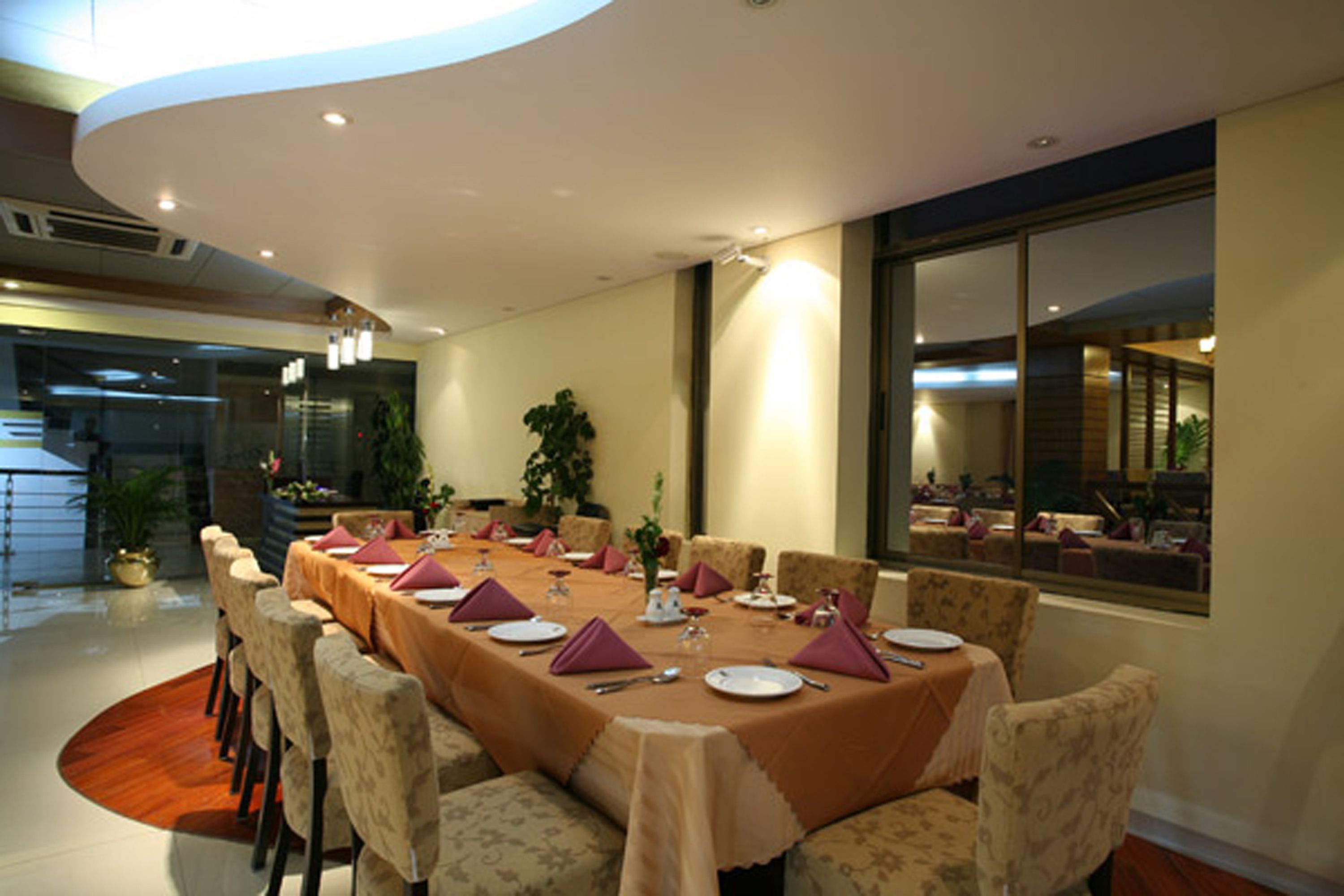 A dining area with a long table set for a meal, surrounded by upholstered chairs.
