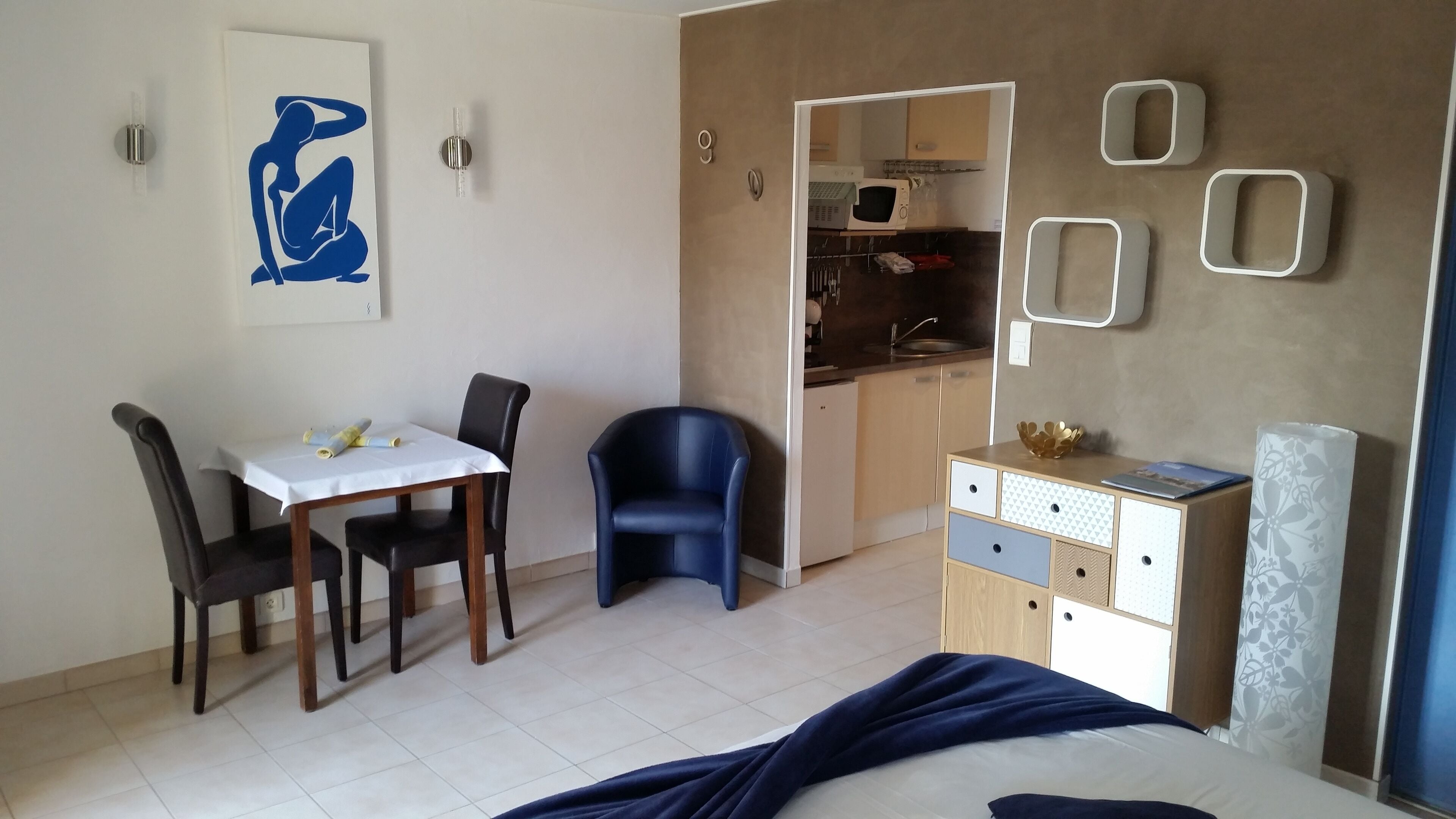 Habitación compacta con mesa de comedor, sillas, cama, armario y kitchenette.