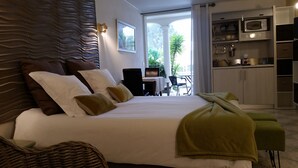 A bedroom with a large bed, a dining area, and a view of the outdoors. - Chambre d'hôtes La Potinière (Saint-Raphael)