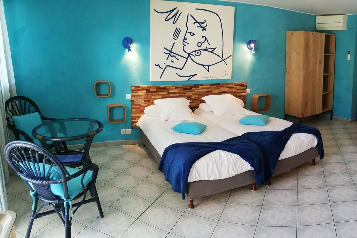 Une chambre à coucher avec un lit, deux chaises, un canapé et des œuvres d’art accrochées aux murs.