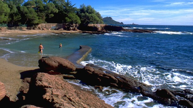 A rocky beach with clear water, a few people, and a distant island. - Chambre d'hôtes La Potinière (Saint-Raphael)