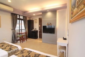 A hotel room with two beds, a TV, a desk, and a chair.
