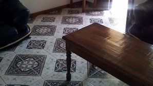 Ein Wohnzimmer mit Fliesenboden mit Muster, einem Holztisch und zwei schwarzen Ledersofas.