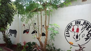 Ein Wandgemälde mit Silhouetten von Tieren, Menschen, einem Baum und einem kreisförmigen Wappen mit Figuren.