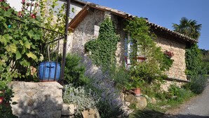 A stone house with a tiled roof, ivy-covered walls, and a gravel path leading to it. - Chez Elise et Gabriel (Mirmande)