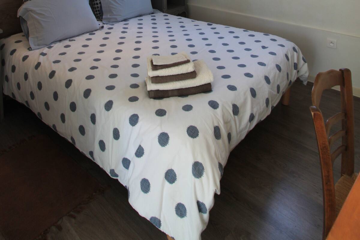 A bedroom with a bed, a nightstand, a lamp, and a window.