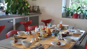A dining table set with various dishes, utensils, and a plant on the windowsill. - Chez Elise et Gabriel (Mirmande)