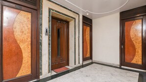 Un pasillo con puertas de madera, un ascensor y suelo de mármol.