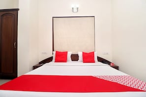 A hotel room with a large bed, two red pillows, a wooden headboard, and a red and white bedspread. - OYO 18964 Hotel Temple View (Amritsar)