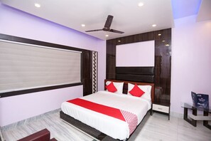 Un dormitorio moderno con una cama grande, un ventilador de techo y una mesita de noche con un libro.