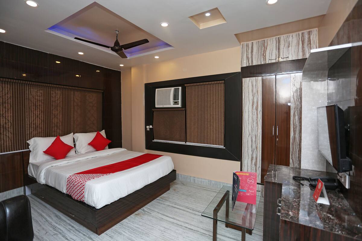 Ein Hotelzimmer mit Bett, Schreibtisch, Fernseher und Deckenventilator.