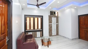 A modern living room with a glass coffee table, a red sofa, and a ceiling fan.