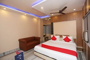 Una habitación de hotel moderna con una cama grande, un sillón marrón y un ventilador de techo.
