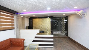 A reception area with a modern design, featuring a reception desk, a brown leather sofa, and a glass-top table.