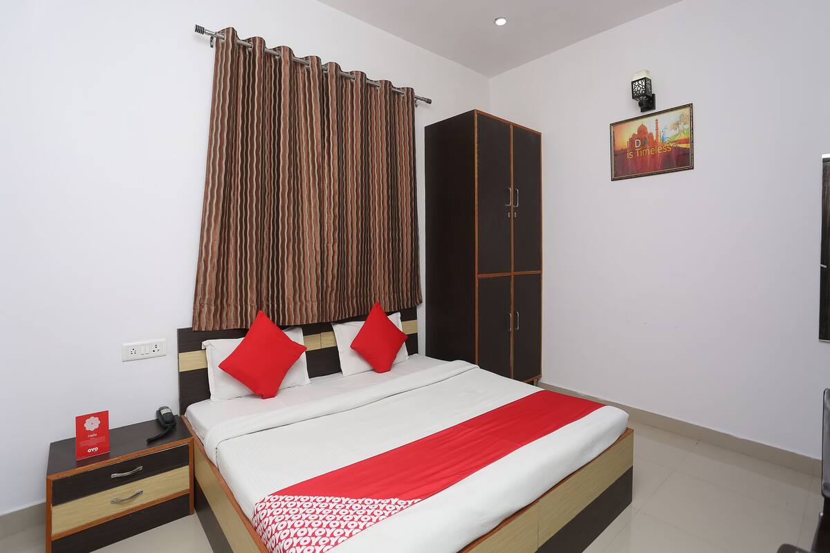 A hotel room with a bed, a wardrobe, a nightstand, and a wall-mounted picture.