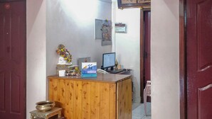 A reception desk with a computer, a telephone, and a small shrine with flowers. - OYO 27809 Hotel Ganapathy Garden (Kodaikanal)