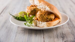 Ein Teller mit zwei frittierten Snacks in einem Brötchen, garniert mit einer Limettenscheibe und Koriander.