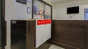 Un área de recepción con un mostrador de madera, obras de arte enmarcadas en la pared y un televisor de pantalla plana montado sobre el mostrador.