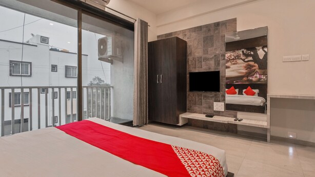 Un dormitorio moderno con una cama grande, un televisor montado en la pared y un balcón con vistas a edificios.