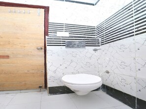 Une salle de bain avec des toilettes, une porte en bois et des murs carrelés.