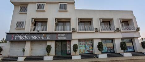 A multi-story building with a signboard for 'Siddhivinayak Brand' offering services like AC restaurant, AC lodging, AC conference, and AC banquet hall.