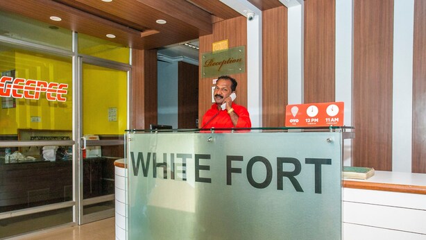Una recepción con un cartel que dice "WHITE FORT" y un hombre con una camisa roja detrás.