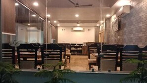 Uma sala de conferências com fileiras de cadeiras, um ventilador de teto e um aparelho de ar condicionado na parede.