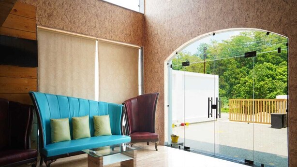 Um interior moderno com um sofá azul, uma poltrona escura e uma mesa de centro de vidro.