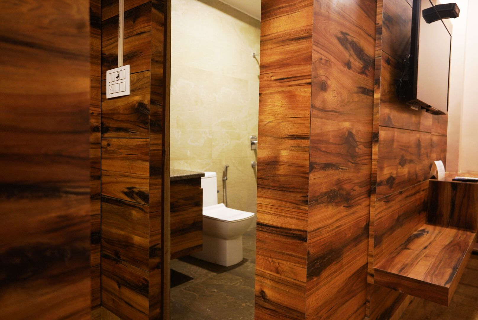 Un bagno con rivestimenti in legno, un water, un lavandino e uno specchio.