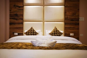 A hotel room with a large bed, a wooden headboard, and two decorative pillows. - Panambi Resort Rishikesh (Yamkeshwar)