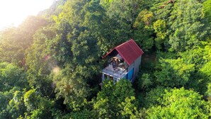 An aerial view of a small, isolated cabin surrounded by dense forest. - Arangala Forest Lodge (Naula)