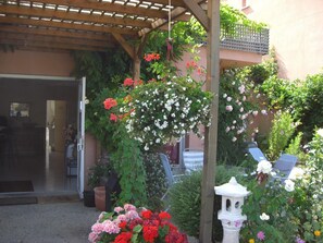 A covered outdoor area with a pergola, potted plants, and a white decorative structure. - Hotel Au Sans Souci (Chinon)
