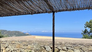 Un muro de piedra con vista al océano y montañas en la lejanía.