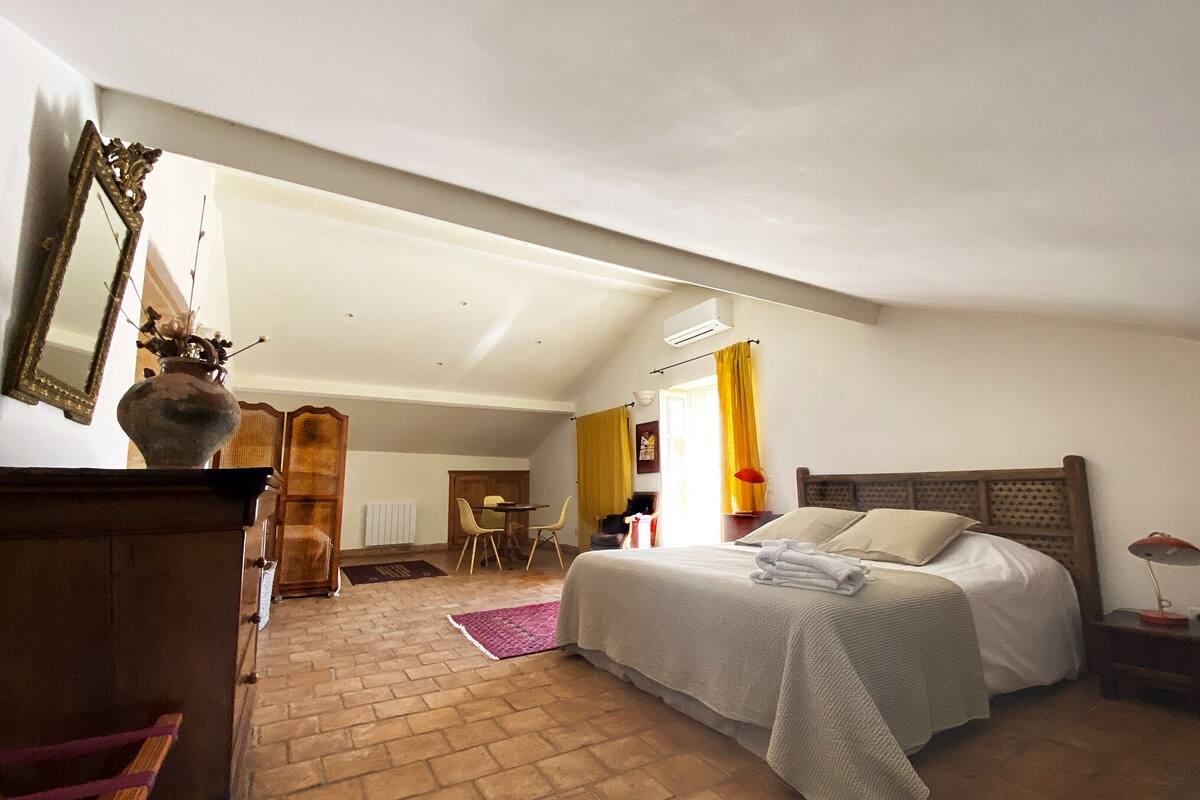 Ein Schlafzimmer mit Bett, Schminktisch, Spiegel und einem Fenster mit Vorhängen.