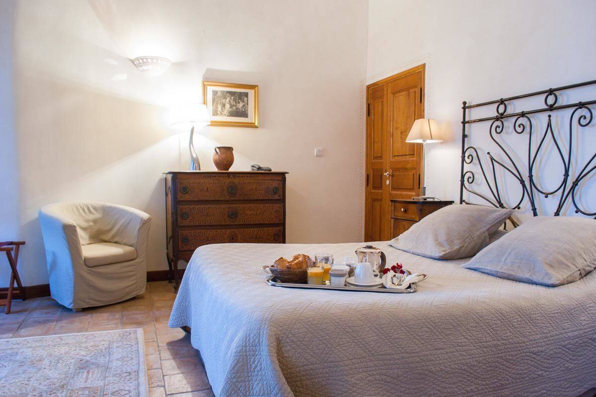 Ein Schlafzimmer mit einem Bett, einer Holzkommode, einem Sessel und einem Tablett mit Frühstücksgebäck.