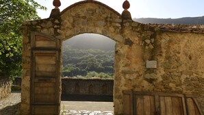 Un antiguo arco de piedra con una puerta y un portón de madera, que conduce a un sendero de piedra.