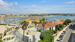 A coastal marina with boats, a sandy beach, and buildings with red-tiled roofs. - Apartment Praia Rocha Justar Cozy (Portimão)