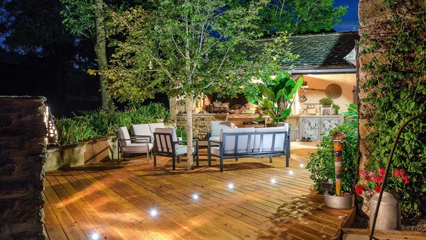 Eine Terrasse im Freien mit Holzboden, Sitzgelegenheiten und Blumentöpfen.