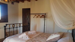 A bedroom with a bed, a hanging clothes rack, and a door. - BERLANGA DE DUERO, CAÑÓN DE RÍO LOBOS BURGO DE OSMA, SAN BAUDELIO, (Bayubas de Abajo)