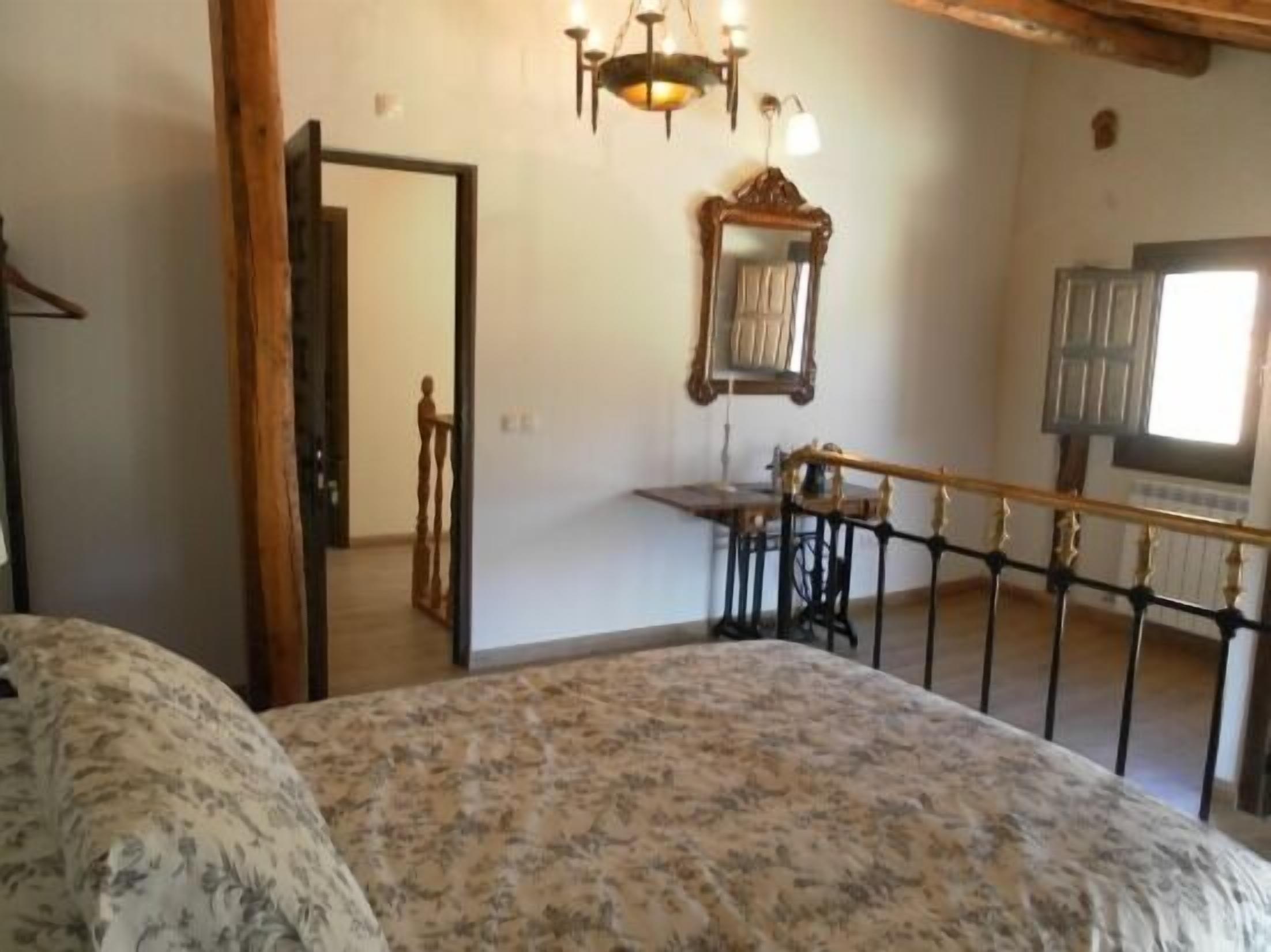 Une chambre à coucher avec un lit, un bureau en bois, un miroir et une fenêtre.