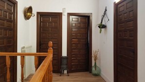 A hallway with wooden doors, a radiator, a small table, and a hanging plant. - BERLANGA DE DUERO, CAÑÓN DE RÍO LOBOS BURGO DE OSMA, SAN BAUDELIO, (Bayubas de Abajo)
