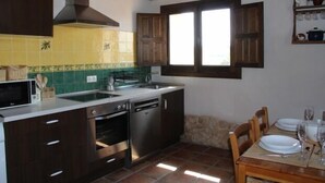 A kitchen with a sink, stove, and dishwasher. There is a dining table with chairs and a window above it. - BERLANGA DE DUERO, CAÑÓN DE RÍO LOBOS BURGO DE OSMA, SAN BAUDELIO, (Bayubas de Abajo)