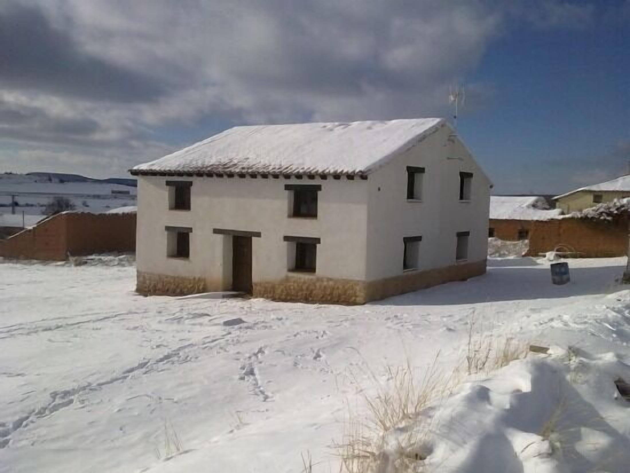 Un edificio de dos pisos con techo nevado y una entrada pequeña.
