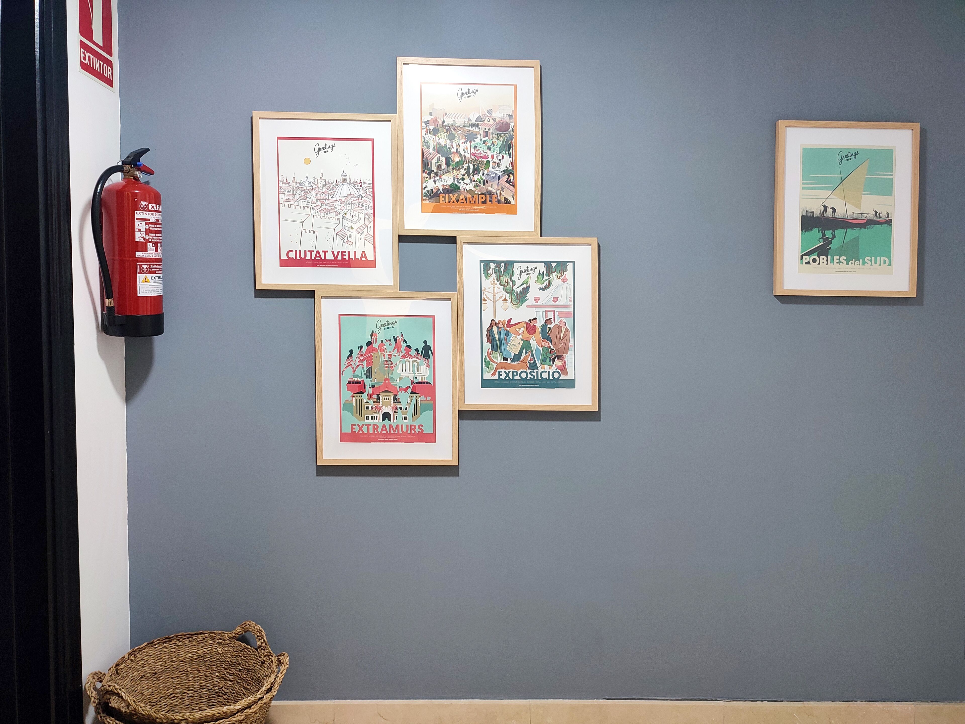 Una pared con cinco ilustraciones enmarcadas y un extintor.