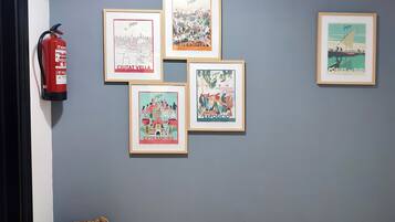 Una pared con cinco ilustraciones enmarcadas y un extintor.