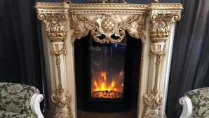 Una chimenea con detalles dorados ornamentales y fuego encendido en su interior.